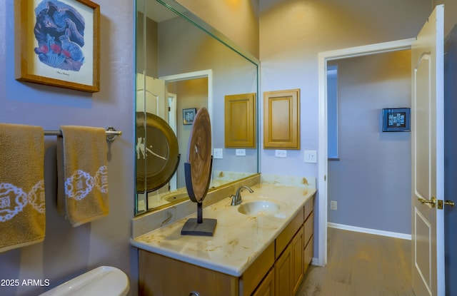 bathroom featuring toilet, vanity, baseboards, and wood finished floors