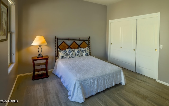 bedroom with a closet, wood finished floors, and baseboards