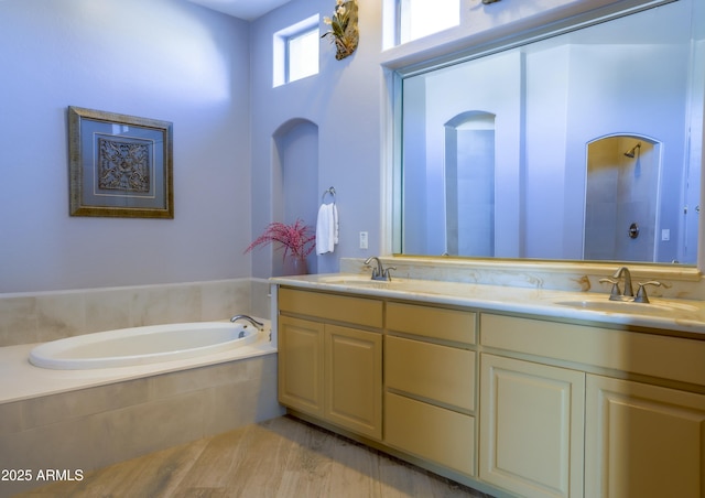 full bathroom with a tile shower, double vanity, tiled bath, and a sink