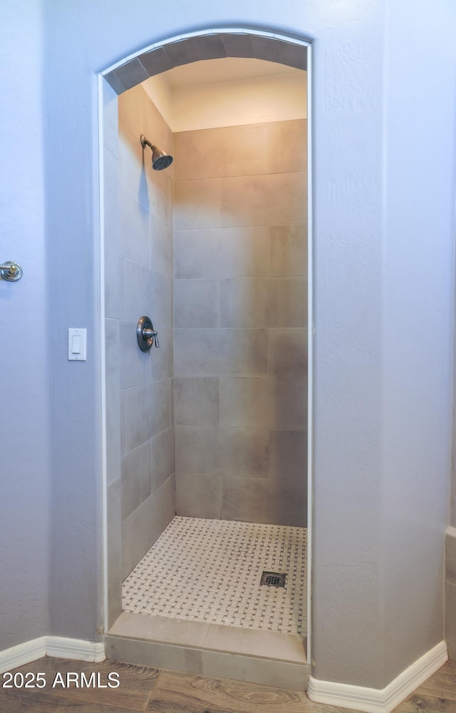 full bath with a shower stall and baseboards