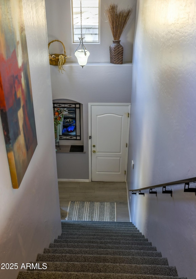 staircase featuring a towering ceiling and wood finished floors