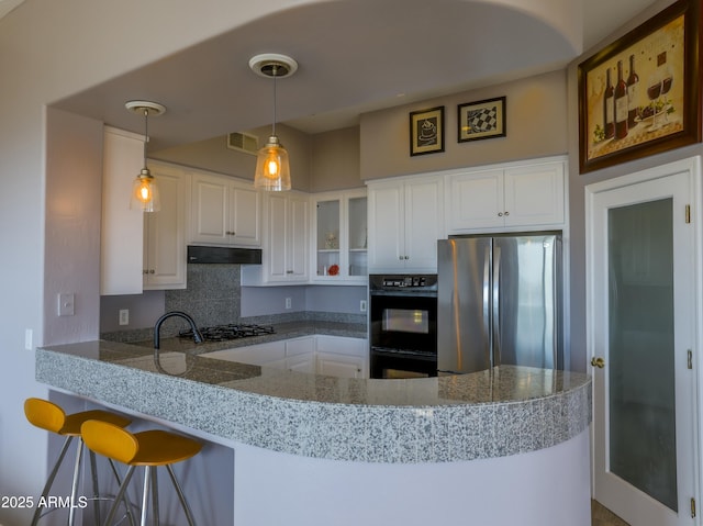 kitchen with stainless steel appliances, glass insert cabinets, white cabinetry, a peninsula, and under cabinet range hood