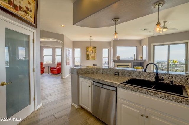 kitchen with open floor plan, stainless steel dishwasher, a sink, and white cabinets