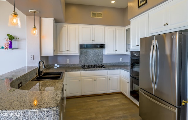 kitchen with visible vents, white cabinets, freestanding refrigerator, range hood, and a sink