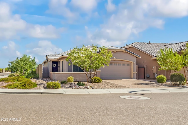 view of front of home with a tile roof, a garage, driveway, and stucco siding