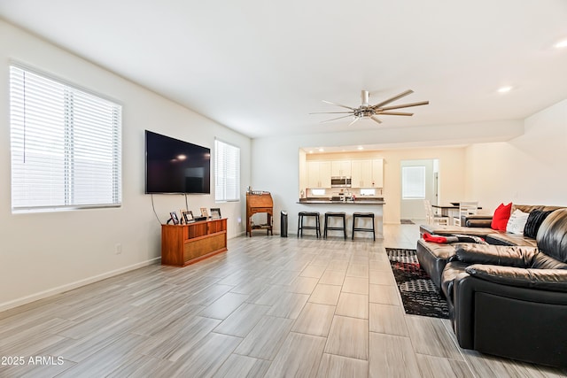 living room featuring baseboards and a ceiling fan