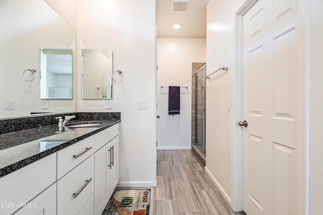 bathroom with visible vents, a shower stall, vanity, and baseboards