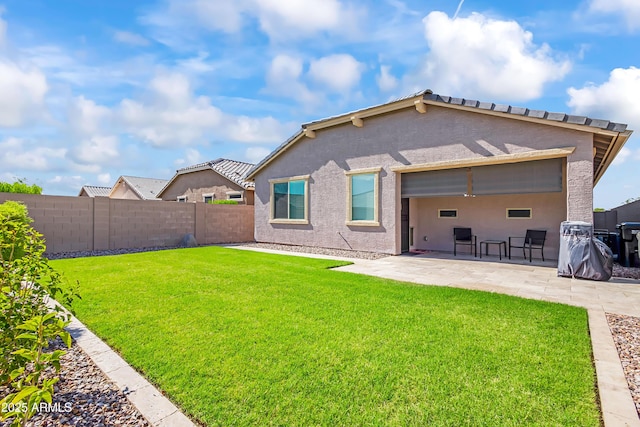 rear view of house with a patio area, a lawn, a fenced backyard, and stucco siding