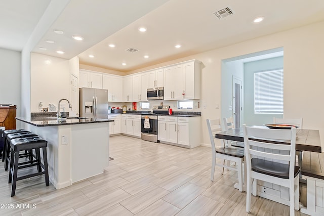 kitchen with a sink, stainless steel appliances, visible vents, and a peninsula