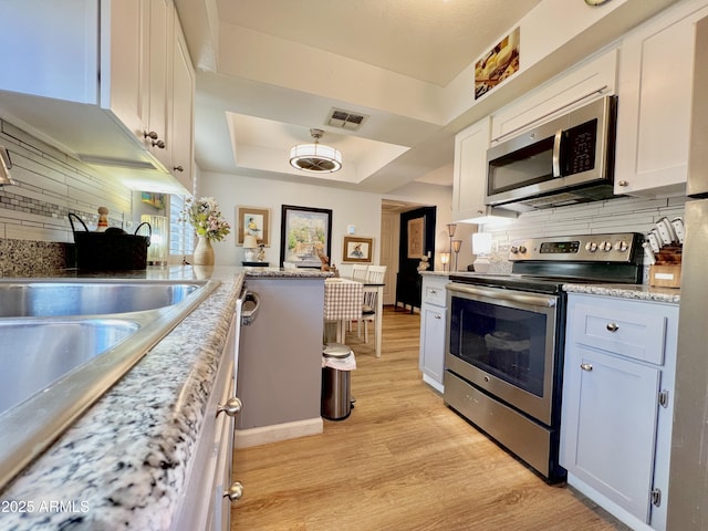 4554 E Paradise Village Pkwy N Unit 133, Phoenix, AZ 85032 - kitchen featuring stainless steel appliances, light wood-style flooring, decorative backsplash, and white cabinets