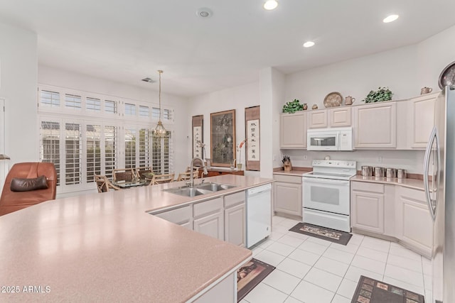 kitchen featuring pendant lighting, a sink, light countertops, white appliances, and light tile patterned flooring