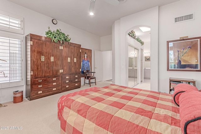 bedroom featuring arched walkways, ensuite bathroom, carpet, and visible vents
