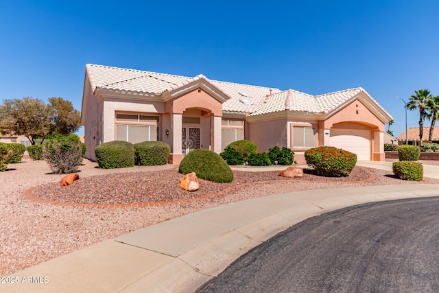 mediterranean / spanish-style house featuring a tiled roof, stucco siding, driveway, and a garage