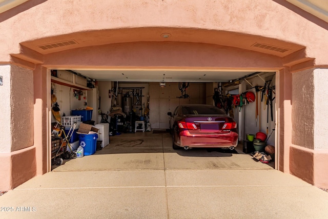 garage with visible vents, water heater, and driveway