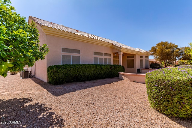 exterior space with stucco siding, cooling unit, and a tiled roof