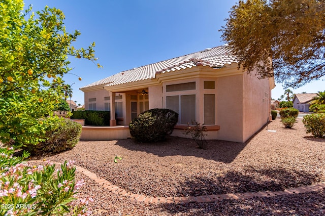 rear view of house featuring a tiled roof, ceiling fan, and stucco siding
