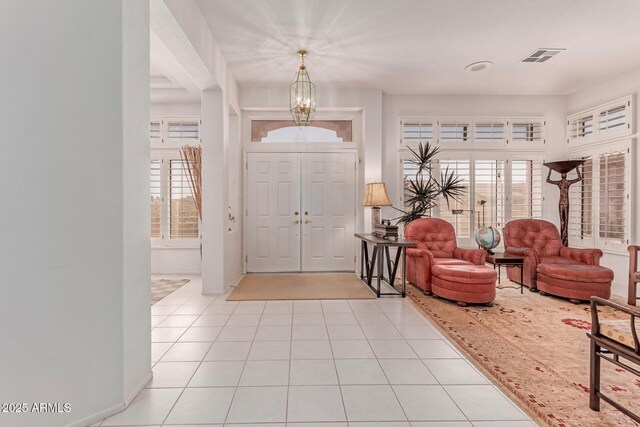 foyer entrance featuring visible vents, baseboards, light tile patterned floors, and a notable chandelier