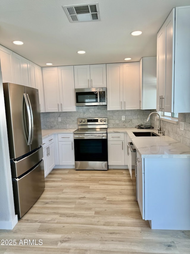 3014 W Zachary Dr, Phoenix, AZ 85027 - kitchen with appliances with stainless steel finishes, white cabinets, light stone countertops, light wood-style flooring, and recessed lighting