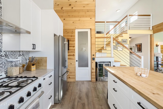 kitchen featuring stainless steel fridge, wine cooler, white range, a high ceiling, and white cabinetry