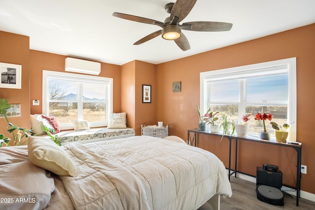 bedroom with multiple windows, ceiling fan, a wall mounted AC, and wood-type flooring