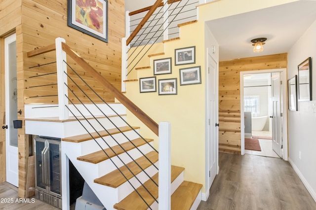 stairway with wood walls, wood-type flooring, a fireplace, and wine cooler