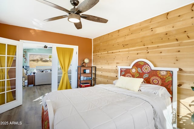 bedroom featuring wooden walls, hardwood / wood-style floors, and ceiling fan