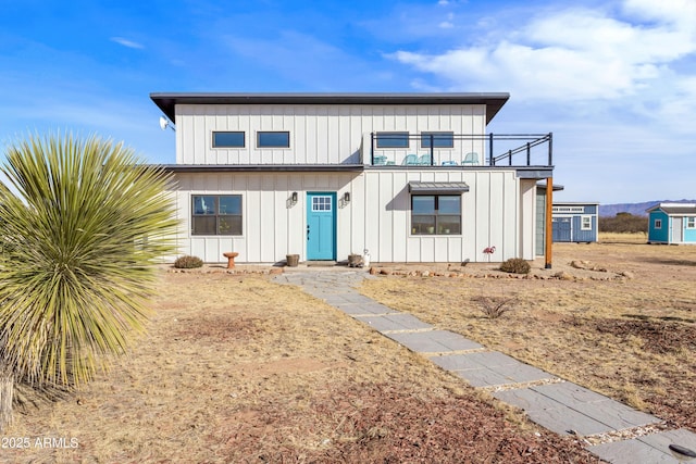 view of front of property featuring a balcony and a shed