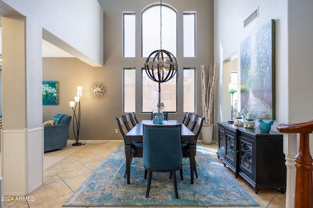 dining room with a notable chandelier, a towering ceiling, and light tile patterned floors