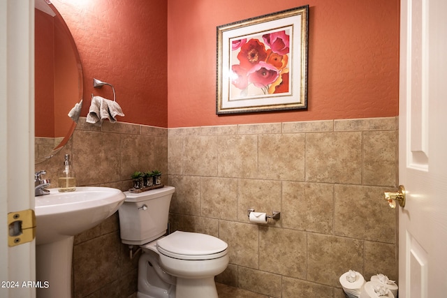 bathroom with sink, tile walls, and toilet