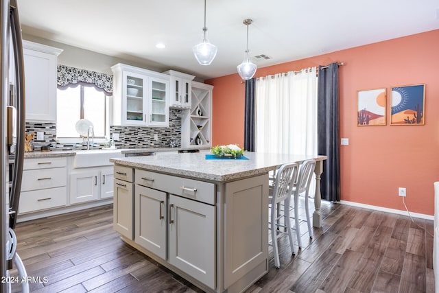 kitchen featuring a kitchen island, backsplash, white cabinetry, and dark hardwood / wood-style flooring