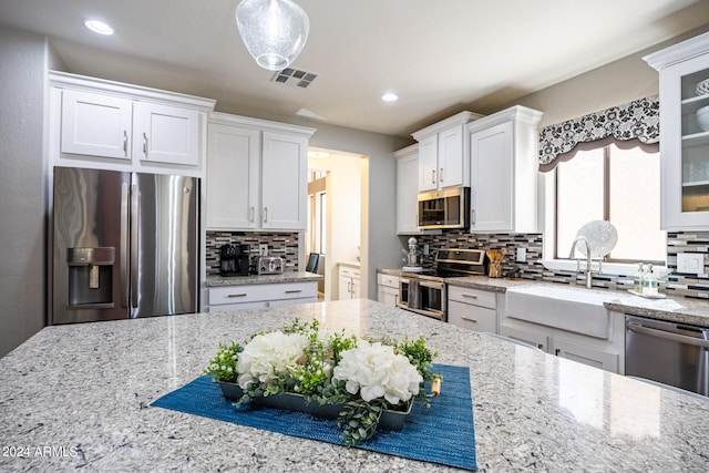 kitchen featuring stainless steel appliances, white cabinets, tasteful backsplash, and sink