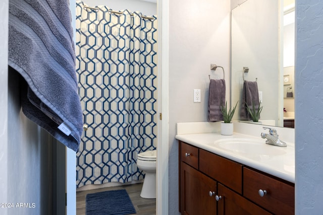 bathroom featuring walk in shower, vanity, hardwood / wood-style floors, and toilet