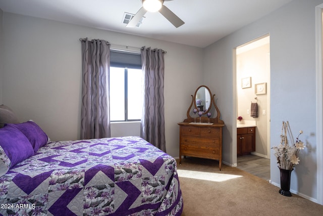 bedroom featuring light carpet, ensuite bath, and ceiling fan