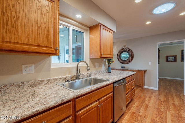 kitchen with light stone counters, sink, stainless steel dishwasher, and light wood-type flooring