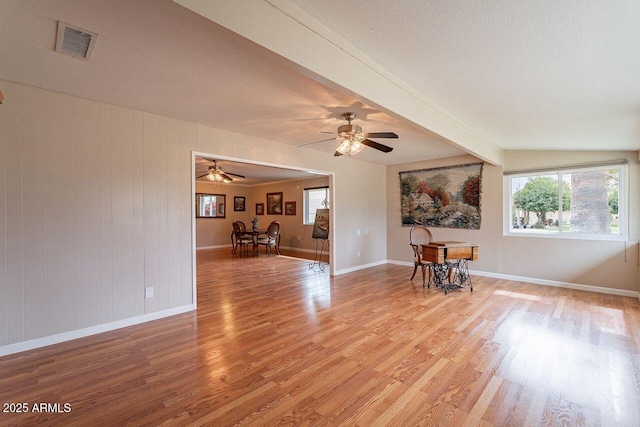 spare room with ceiling fan, a textured ceiling, beam ceiling, and light hardwood / wood-style flooring