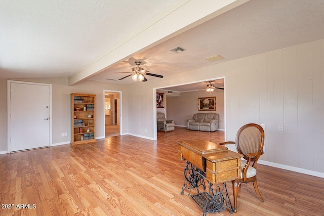 interior space featuring beam ceiling, a textured ceiling, and light hardwood / wood-style floors