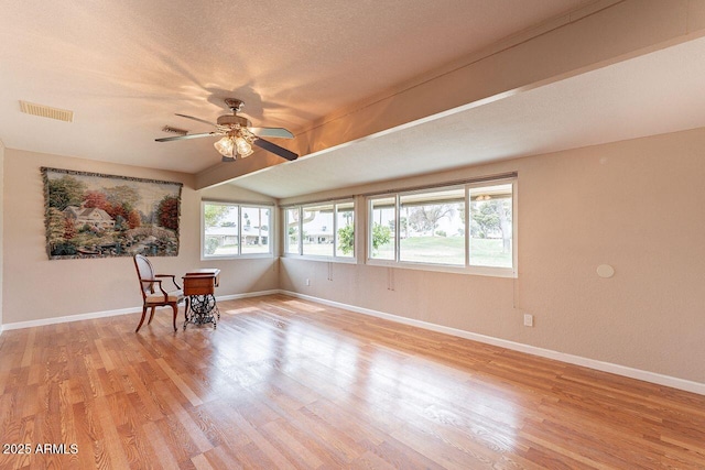 spare room featuring ceiling fan, lofted ceiling, a textured ceiling, and light hardwood / wood-style flooring