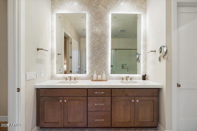 full bath with double vanity, backsplash, a sink, and a shower stall