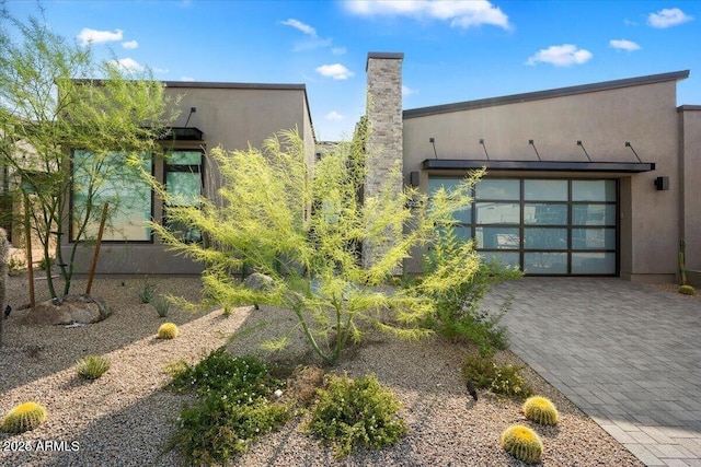 view of front of home featuring decorative driveway, an attached garage, and stucco siding