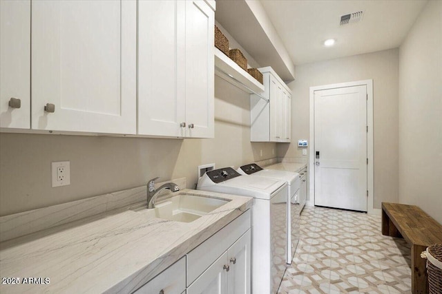 clothes washing area with cabinet space, visible vents, independent washer and dryer, light floors, and a sink