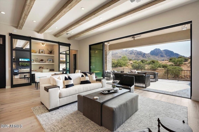 living room with light wood-style floors, a mountain view, beamed ceiling, and recessed lighting