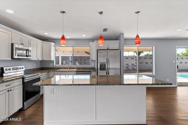 kitchen with appliances with stainless steel finishes, dark wood-type flooring, and a center island