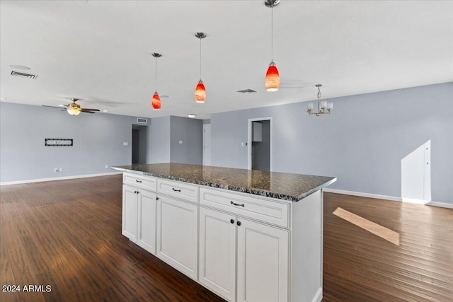 kitchen featuring a center island, white cabinets, dark wood-type flooring, dark stone counters, and decorative light fixtures