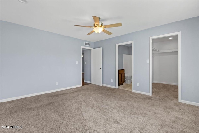 unfurnished bedroom featuring a walk in closet, ensuite bathroom, ceiling fan, light carpet, and a closet