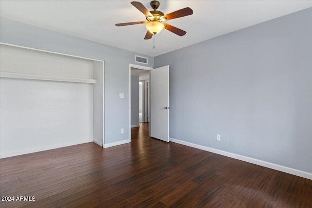 unfurnished bedroom with ceiling fan, a closet, and dark wood-type flooring