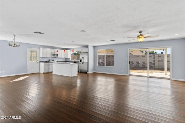 unfurnished living room featuring ceiling fan with notable chandelier, dark hardwood / wood-style floors, and a textured ceiling