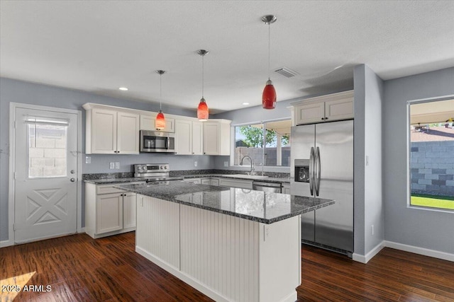 unfurnished living room with baseboards, ceiling fan with notable chandelier, dark wood finished floors, and visible vents