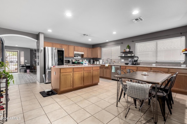 kitchen featuring a kitchen island, light tile patterned floors, and stainless steel appliances