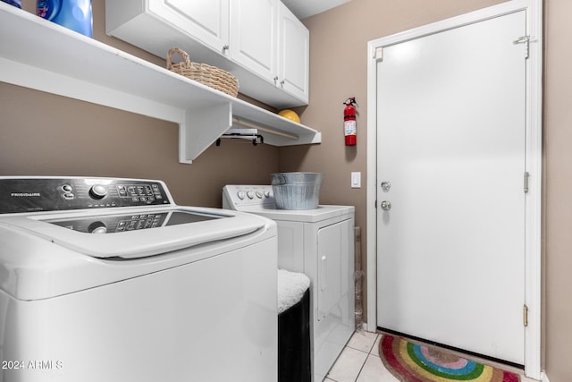 clothes washing area featuring light tile patterned flooring, cabinets, and washing machine and clothes dryer