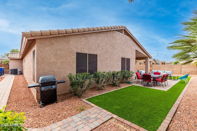 rear view of property with outdoor lounge area, central AC unit, a patio area, and a lawn